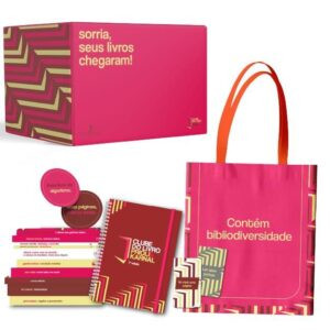 Flat‑lay da edição limitada 2026 do Box Clube do Livro com 10 livros de capa exclusiva, planner, ecobag, marcador magnético, caneca e vela aromática.