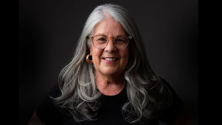 Cláudia Alves, gerontóloga, cuidando de um idoso com Alzheimer, com ícones do método CAPER ao fundo.