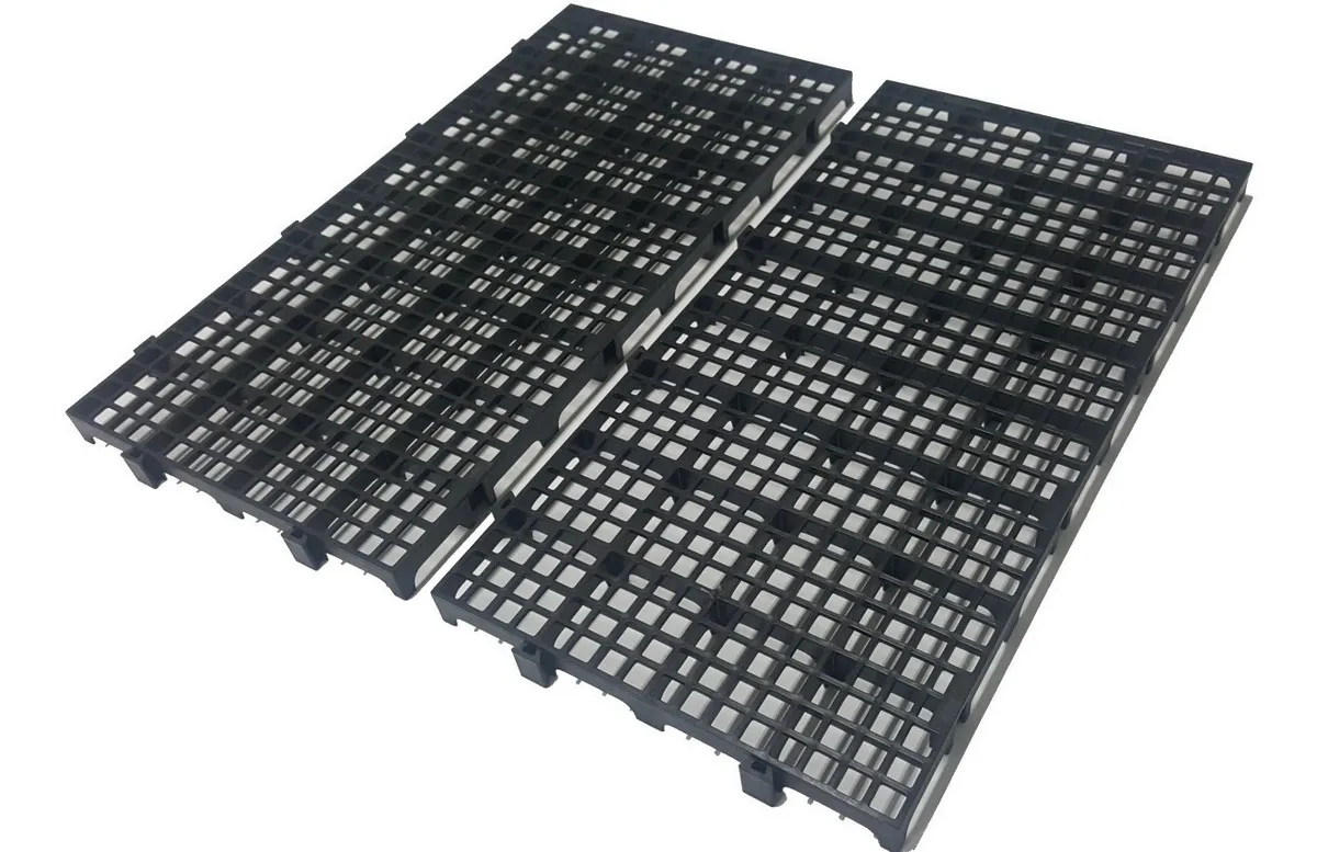 Conjunto de 10 pallets plásticos pretos Marwell 25x50cm montados como piso modular em garagem, mostrando uso doméstico e para canil de pets